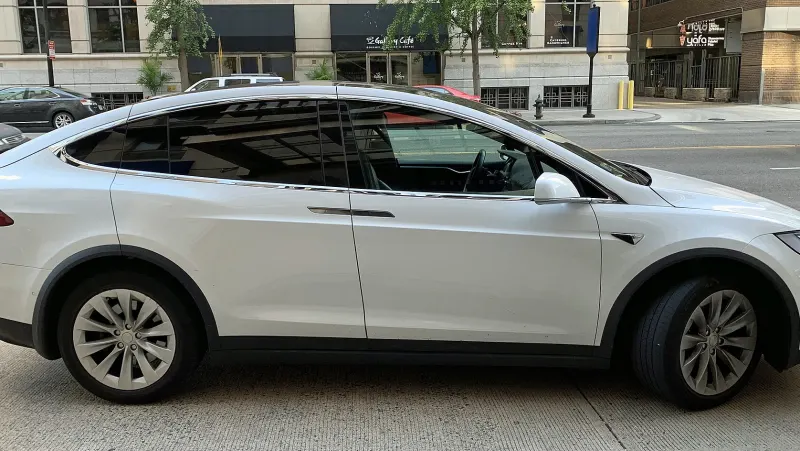 White Tesla Model X parked at a city kerb, seen from the side